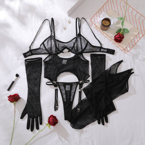 Top-down flat lay presentation of the complete 5-piece KissKismet set, featuring the front-clasp bra, wrap-around garter, thong, sheer gloves, and stockings.