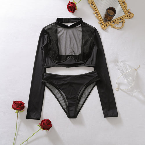 A full flat lay of the two-piece black sheer mesh long-sleeve lingerie top and cut-out panty set, styled with red roses.