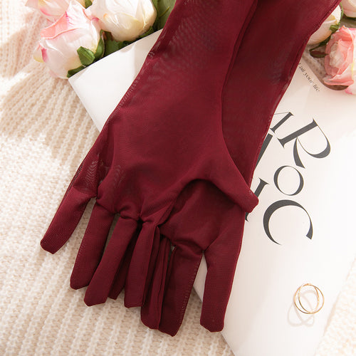 Close-up flat lay showcasing the fine texture and elegant length of the burgundy sheer mesh opera gloves.