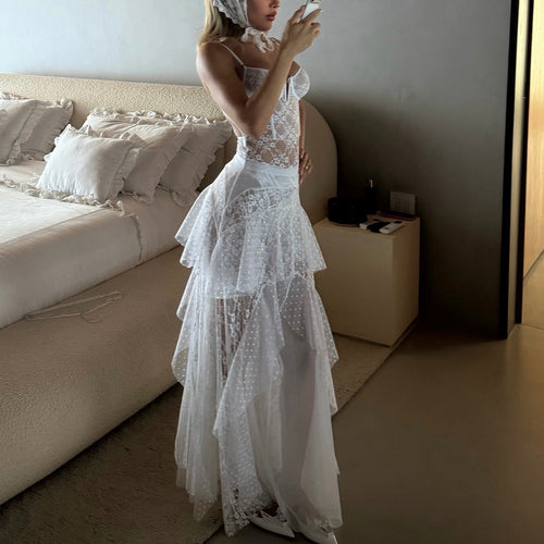 Model standing in a bedroom showcasing the full length and ethereal drape of the sheer white maxi lingerie dress.   