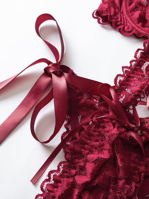 Detailed view of the adjustable ribbon shoulder straps and scalloped lace edges on the KissKismet red bodysuit.