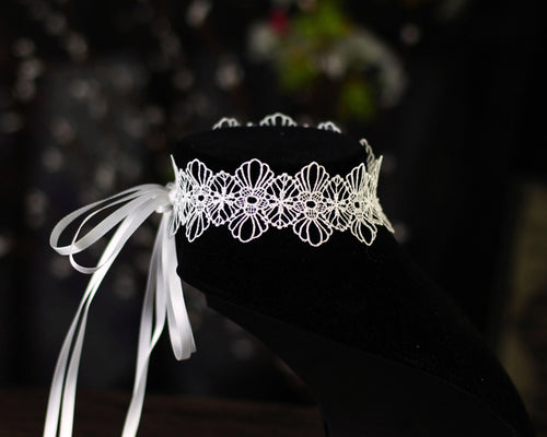Close-up of adjustable white satin ribbon bow tie closure on back of lace choker necklace.