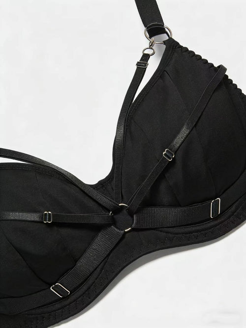 Extreme close-up detailing the durable metallic hardware and high-quality adjustable strap construction of the structural black lingerie.
