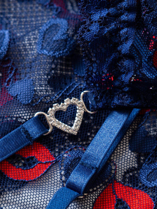 Close-up flat lay highlighting the durable adjustable straps and rhinestone heart hardware of the sheer mesh chemise.