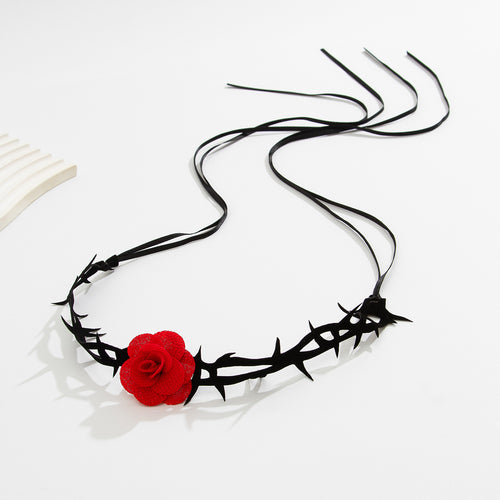 Full length flat lay of the gothic thorn thigh garter showing the long adjustable black tie ribbons and red rose.