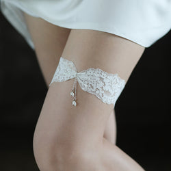 Slightly wider on-body shot showing the elegant placement of the white lace tassel garter on a model’s upper thigh.