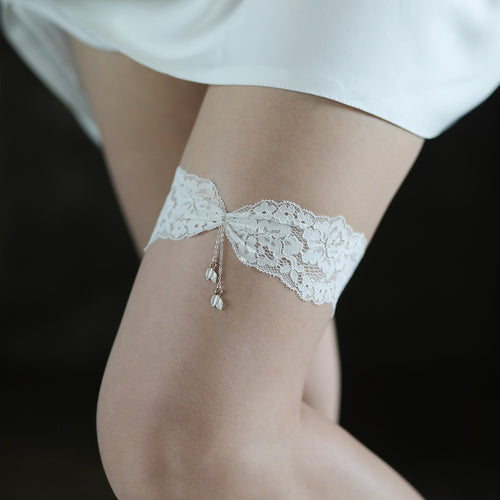 Slightly wider on-body shot showing the elegant placement of the white lace tassel garter on a model’s upper thigh.