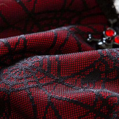 Macro shot of the striking black spiderweb lace overlay on a deep red fabric base.