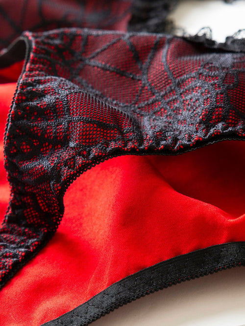 Close-up showing the soft red inner lining and leg opening of the spiderweb lace bodysuit.