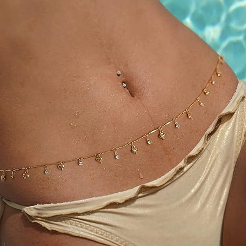 Close-up of a delicate gold heart and rhinestone waist chain worn over a metallic gold bikini bottom by the pool.