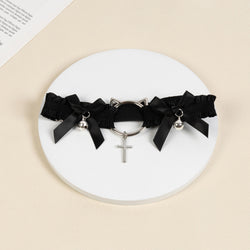 Flat lay view of the black ruffled thigh garter displaying the silver cat-ear hardware, ribbon bows, and cross pendant.