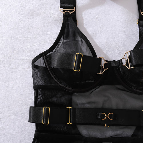 Close-up flat lay of the bodysuit's upper section, showing the sheer underwire cups, gold hardware, and harness neck straps.