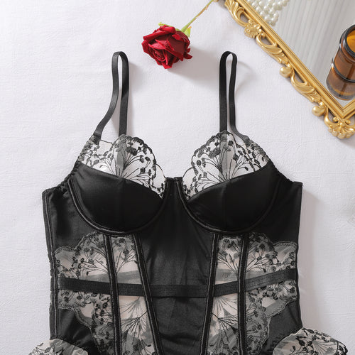 Close-up flat lay of the black satin cups and sheer floral mesh bodice of the corset.