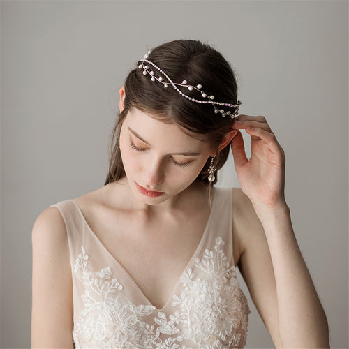 A bride gently adjusting the delicate silver alloy and pearl bridal headband in her hair.