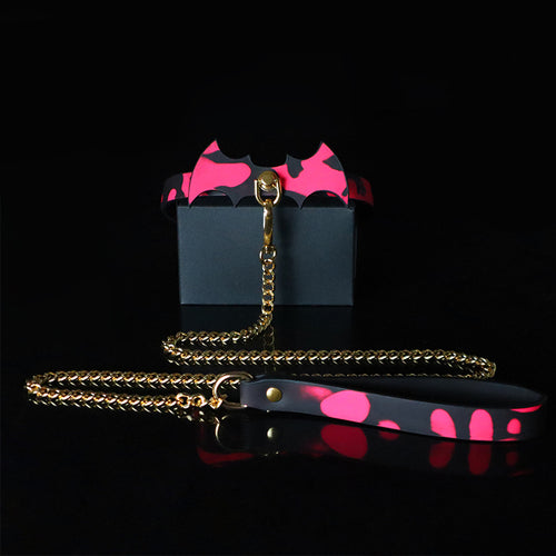 Dark aesthetic display of the heat-reactive red leather bat collar and gold chain leash.