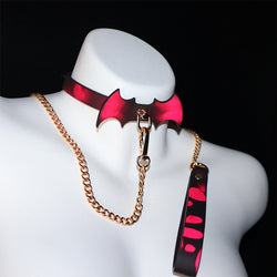 Front view of a mannequin wearing the heat-activated red bat collar and matching gold chain leash set.