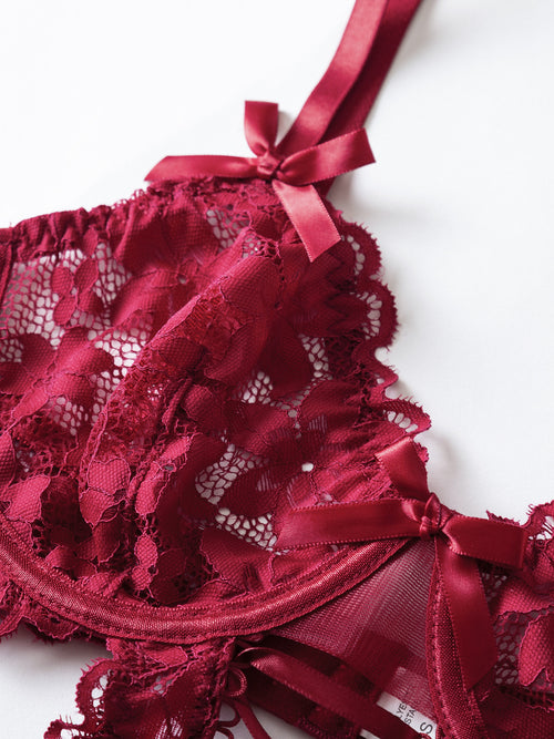 Flat lay presentation of the complete KissKismet crimson lace-up bodysuit, showcasing the corset-style front and garter straps.