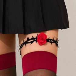 On-body styling shot of the gothic black thorn and red rose garter worn above red stockings and a black skirt.