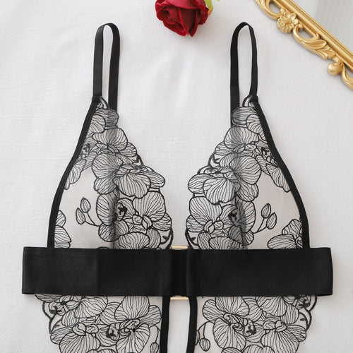 Close-up flat lay of the deep V-neckline and black satin underbust band of the lace bodysuit.