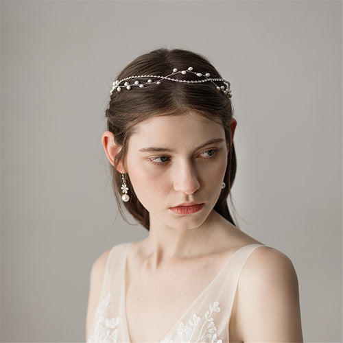 Bride looking down gracefully, highlighting the intricate details of the sparkling rhinestone and pearl hair vine.