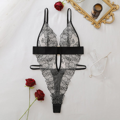 Flat lay view of the black embroidered sheer lace bodysuit on a white surface with red roses.