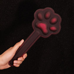 Close-up shot demonstrating the comfortable, ergonomic grip of the KissKismet cat paw impact paddle.