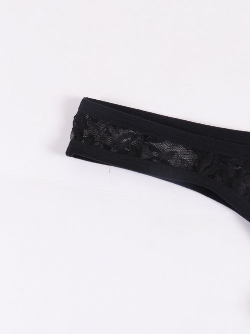 Close-up detail of the sheer floral lace waistband on a black men's thong