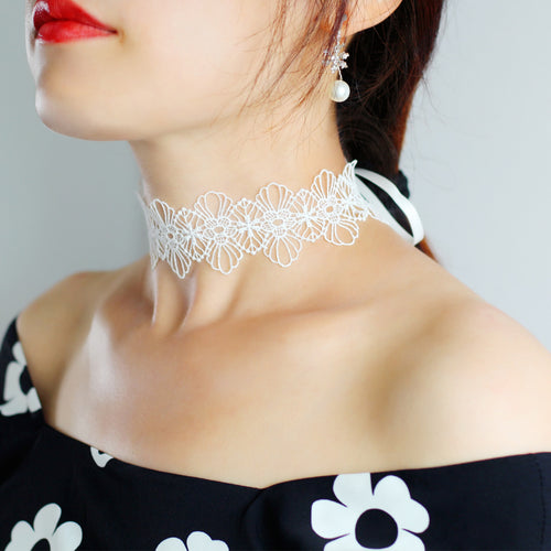 Model wearing delicate white floral embroidered lace choker tied gracefully along the collarbone.