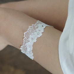 Close-up view of the ethereal white lace wedding garter showing intricate floral embroidery.