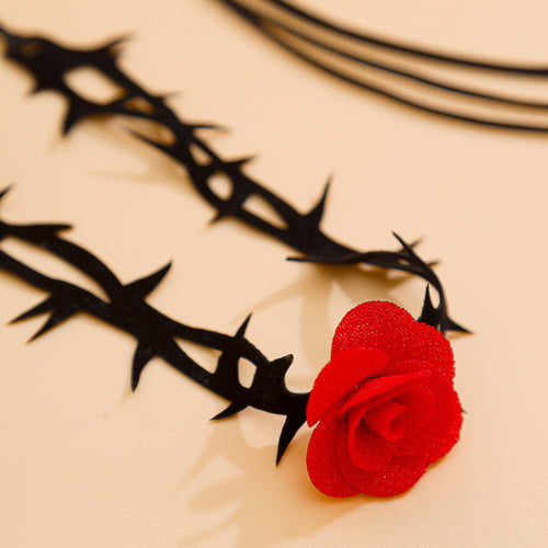 Close-up macro shot highlighting the textured 3D red rose and jagged black thorn details of the leg wrap.
