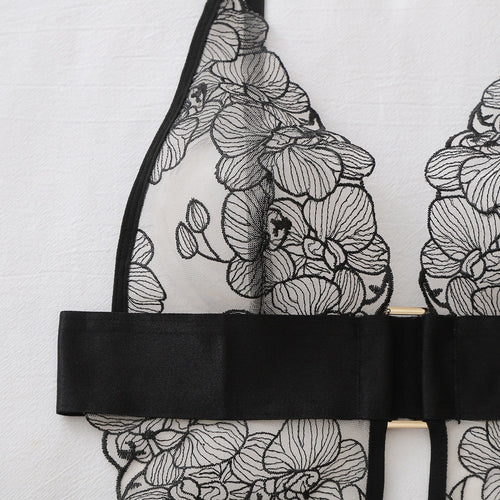 Macro close-up flat lay focusing on the delicate black floral embroidery on sheer mesh.