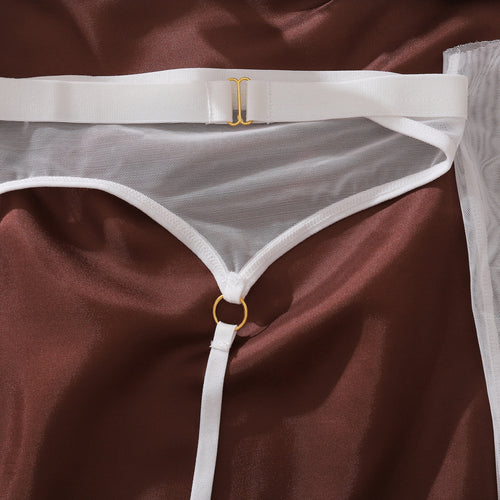 Close-up flat lay detail of the KissKismet ivory sheer mesh thong, highlighting the daring center connecting strap and gleaming gold-tone O-ring.