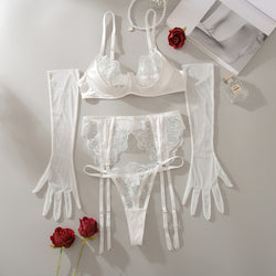 Flat lay presentation of the complete KissKismet 4-piece bridal set, including the V-wire bra, high-waisted garter, thong, and sheer white opera gloves.