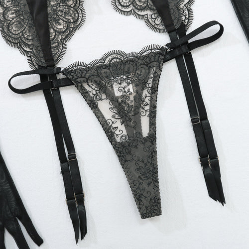 Close-up flat lay detail of the matching sheer nude mesh and black lace thong with adjustable garter straps.