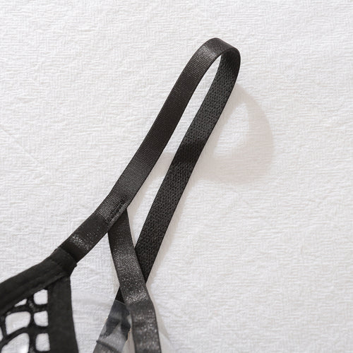 Close-up shot highlighting the high-stretch elastic shoulder straps of the KissKismet black fishnet lingerie top against a textured white background.
