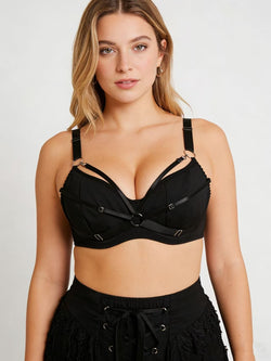 Front lifestyle shot of a curvy model wearing the KissKismet black strappy underwire bra, highlighting the architectural O-ring harness design.