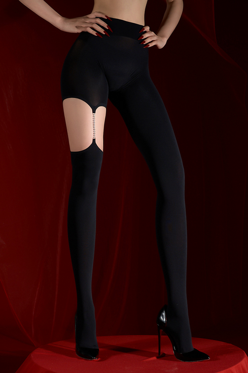 Three-quarter standing view of KissKismet black tights, showcasing the flattering silhouette and asymmetrical rhinestone suspender detail against a deep red background.