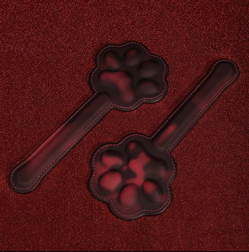Flat lay presentation of two KissKismet cat paw paddles, highlighting the textured 3D paw pad design for sensory play.
