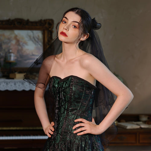 Front view of a model in a dark corset dress wearing the French Hepburn style black tulle veil.