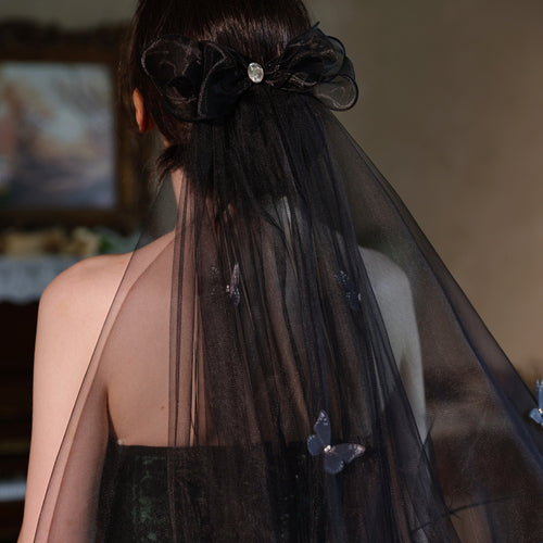 Back view detailing the easy-to-wear hair clip attachment and butterfly accents on the sheer black veil.
