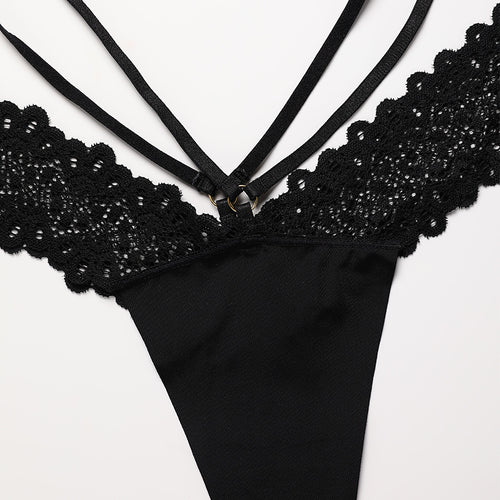 Close-up front flat lay detail of the KissKismet black thong, focusing on the daring V-cut elastic straps and delicate scalloped lace edges.