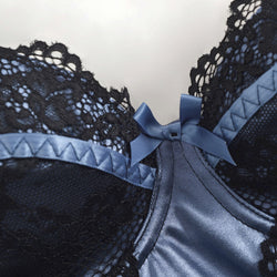 Ultra close-up view focusing on the central blue satin panel, black lace overlay, and small blue bow detail on the structured midnight blue bustier top.