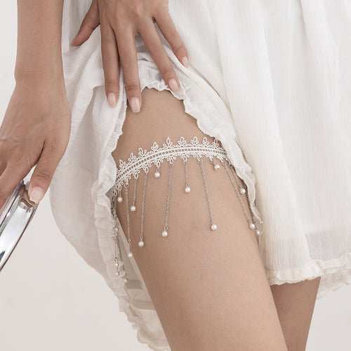 Angled view showing the elegant drape and movement of the silver chains and faux pearls on the white garter.