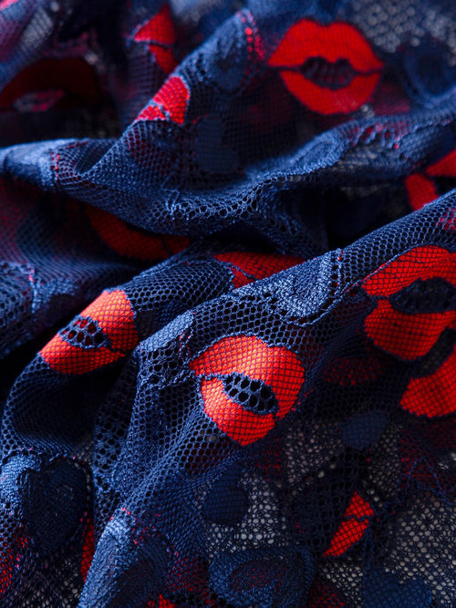 Extreme close-up of the premium sheer navy blue mesh fabric adorned with a playful red lip pattern.