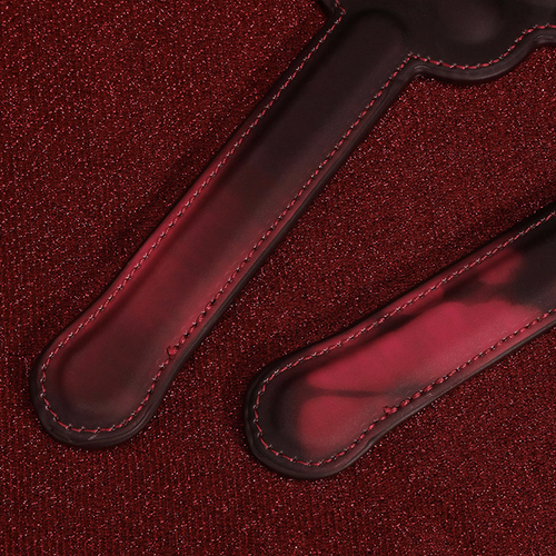 Close-up flat lay focusing on the premium stitching and smooth edge finish of the sensual leather paddle handles.