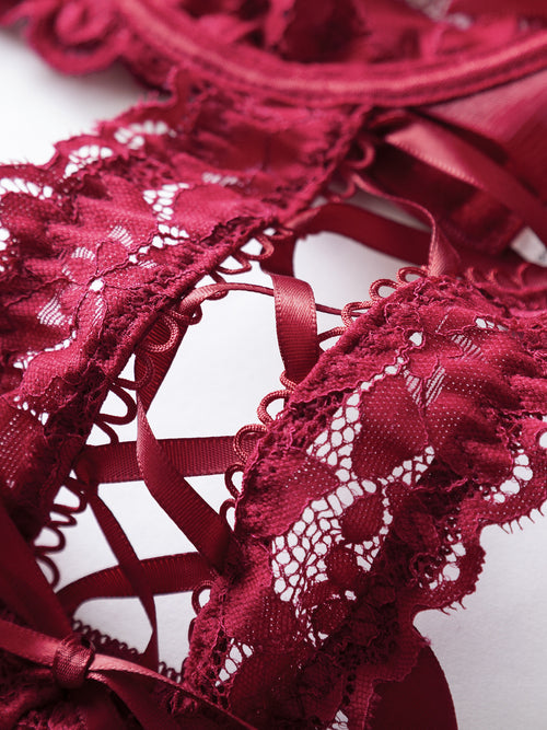 Close-up view of the intricate center cutout and ribbon lacing detail on the crimson floral lace bodysuit.