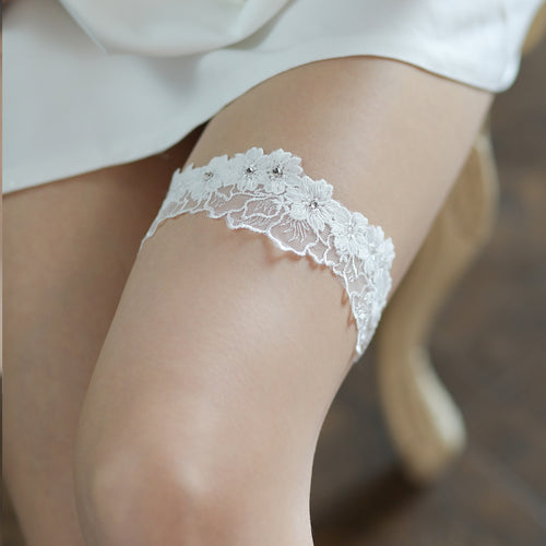 Model sitting gracefully, highlighting the romantic white floral lace garter on her thigh.