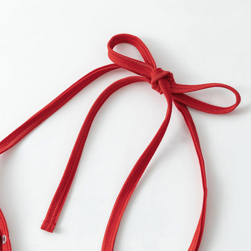 Close-up of the red halter neck tie straps on a metallic swimsuit