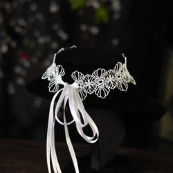 Front display of luxury white floral lace collar choker with draped satin ribbon ties on jewelry stand.