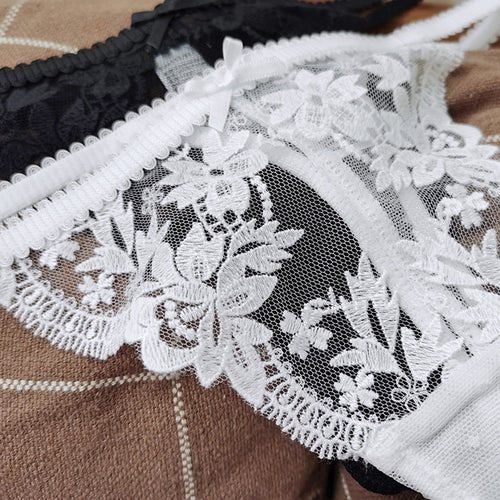Close-up flat lay detail of the exquisite white floral lace embroidery and delicate double side strings on the KissKismet thong.